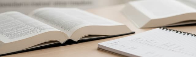 gros plan chaleureux d'un dictionnaire bilingue ouvert et d'un carnet de vocabulaire annoté sur une table en bois claire
