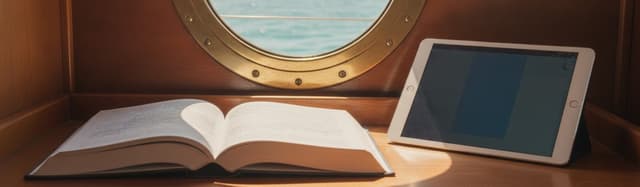 un livre ouvert et une tablette posés sur la table à cartes d'un bateau, hublot avec mer estivale en arrière-plan, lumiè