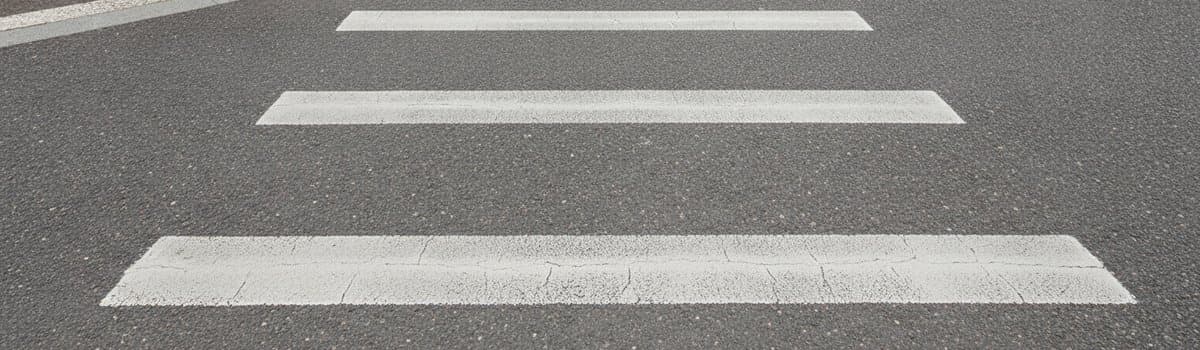 vue rapprochée au ras du bitume d'un carrefour urbain français par temps sec, deux lignes d'arrêt blanches parallèles pe