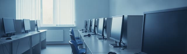 une salle d'examen de langue claire et ordonnée, postes informatiques alignés, un casque audio posé sur une table, une c