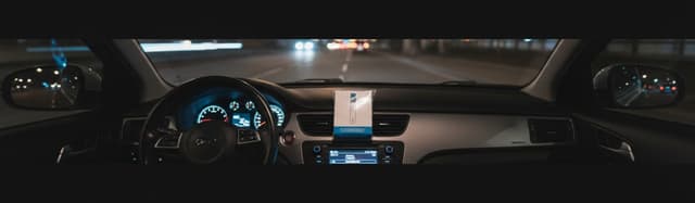 vue de dessus d'un tableau de bord de voiture de nuit, un éthylotest emballé posé sur la console centrale, lumière douce