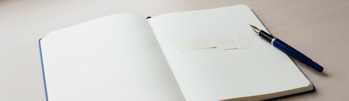 un cahier ouvert avec deux petites étiquettes de papier posées côte à côte sur la page, l'une courte, l'autre découpée e