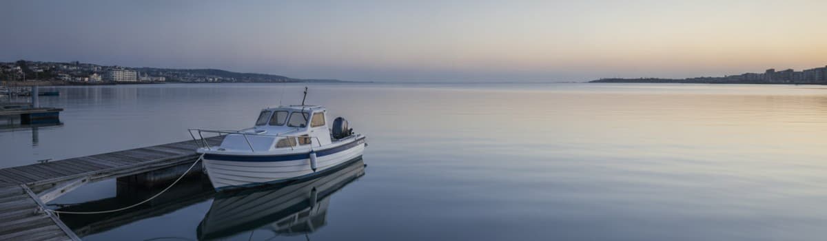ponton de port de plaisance au petit matin, petit bateau à moteur amarré, mer calme, tons bleus