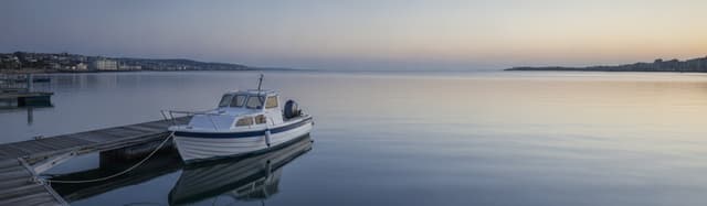 ponton de port de plaisance au petit matin, petit bateau à moteur amarré, mer calme, tons bleus